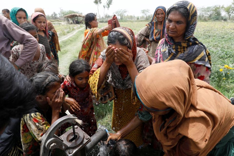 Women and children wash themselves after work at a muskmelon farm (Reuters)