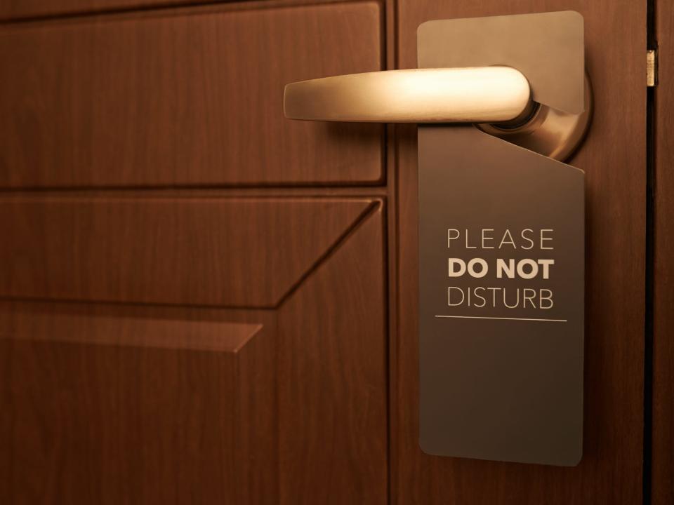 exterior of a hotel room door with a please do not disturb sign hanging on the handle