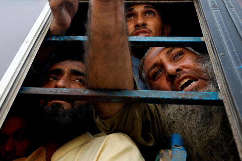 Ciudadanos afganos, que según la policía eran indocumentados, hablan con los miembros de los medios de comunicación desde la ventana de un autobús, mientras eran detenidos y trasladados a un centro de retención temporal, después de que Pakistán diera el último aviso a los inmigrantes indocumentados para que se marcharan, en Karachi