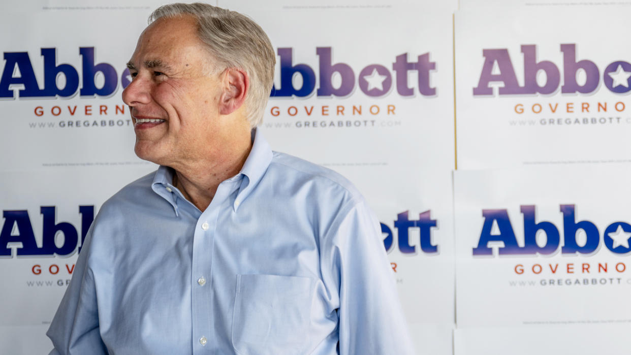 Texas Gov. Greg Abbott stands jubilant in front of a wall posted with signs calling for Abbott Governor.