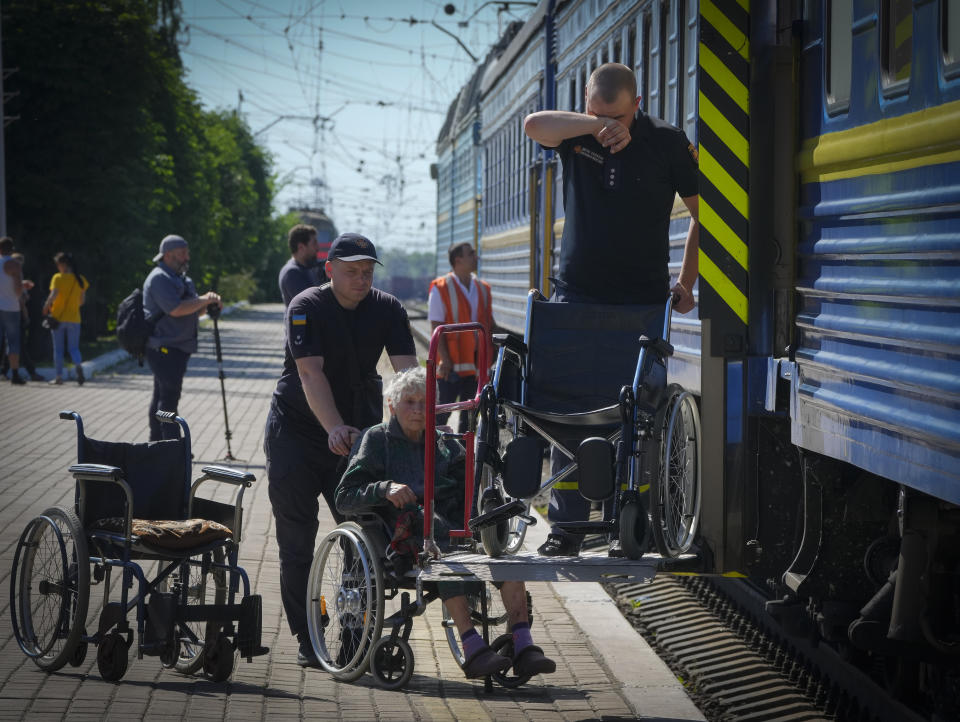 Police officers help a disabled elderly woman get into an evacuation train after she was evacuated from the Lysychansk area in Pokrovsk in eastern Ukraine, Saturday June 11, 2022. (AP Photo/Efrem Lukatsky)