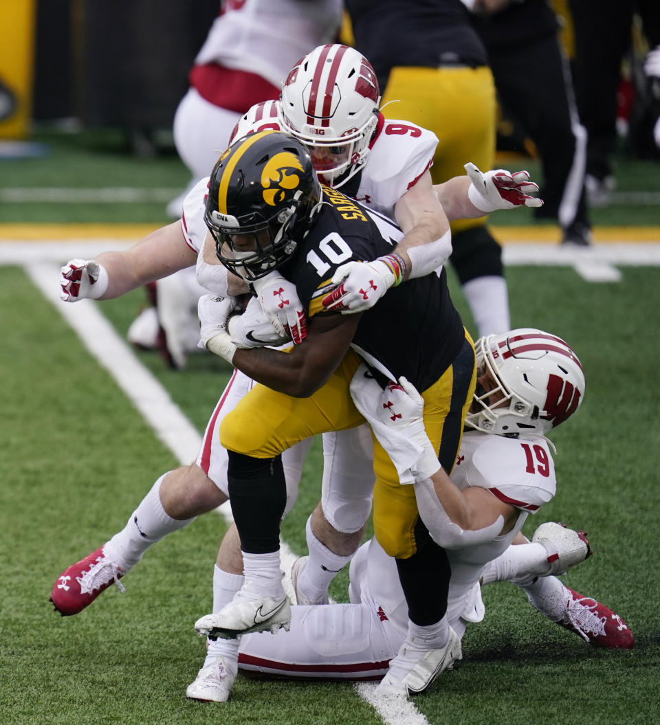 Iowa running back Mekhi Sargent (10) is tackled by Wisconsin safety Scott Nelson (9) and linebacker Nick Herbig (19) during the first half of an NCAA college football game, Saturday, Dec. 12, 2020, in Iowa City, Iowa. (AP Photo/Charlie Neibergall)