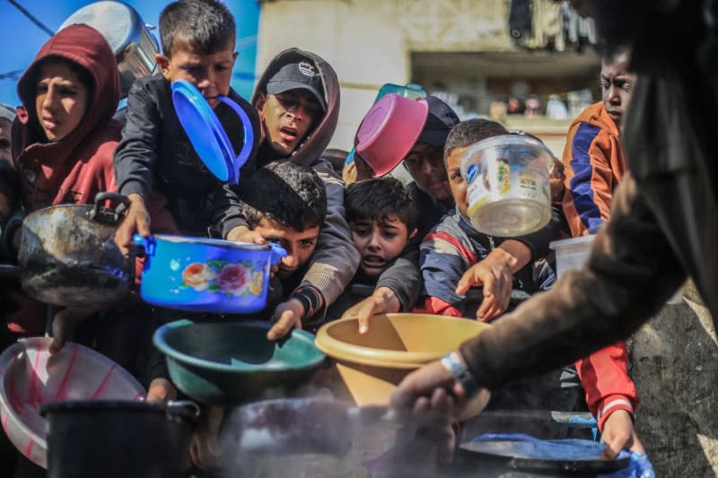 Palestinian children receive food prepared in a charity kitchen. The World Health Organization (WHO) said on Friday that the threat of famine still hangs over the war-torn Gaza Strip. Mohammed Talatene/dpa