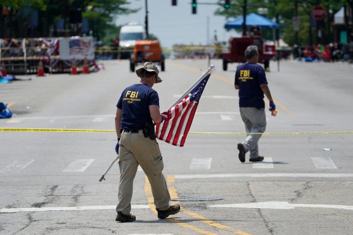 A member of the FBI's evidence response team removes an American flag one day after a mass shooting in downtown Highland Park on Tuesday, July 5, 2022.