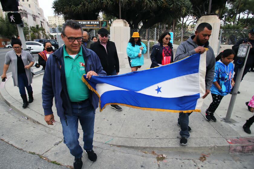 A group of people from Central America and Mexico, hold the Honduras flag as they walk to MacArthur Park to demonstrate and have a vigil in memory of the 38 people who were killed in a fire that broke out at the National Migration Institute Facility along the U.S.-Mexico border in Ciudad Juarez, Mexico, the demonstration took park in MacArthur Park in Los Angeles on Friday, March 31, 2023. (Photo by James Carbone For Los Angeles Times Espanol)