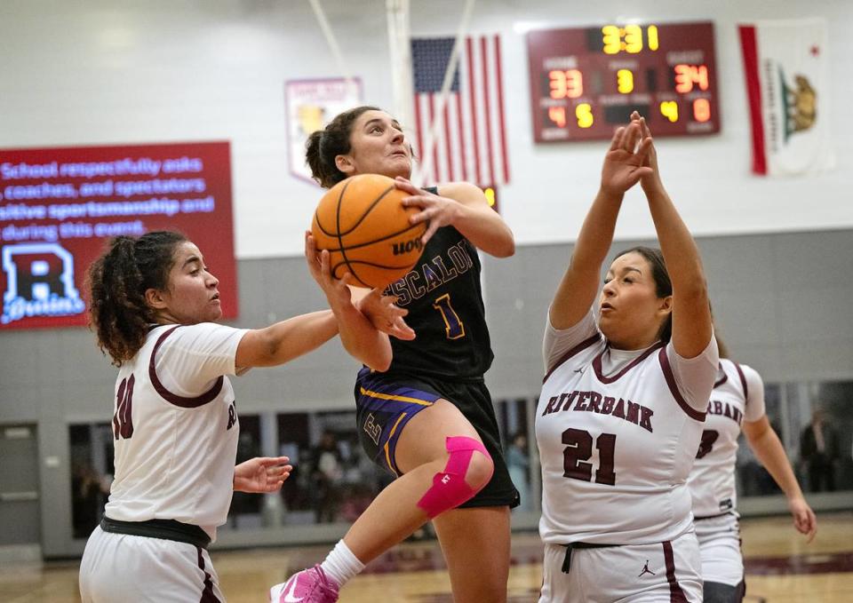 Escalon’s Sammy Lang attacks the basket as Riverbank’s Chancis Gamez, left, and Haley Barker, right defend during the Trans Valley League game at Riverbank High School in Riverbank, Calif., Thursday, Jan. 4, 2024. Escalon won the game 52-51. Andy Alfaro/aalfaro@modbee.com