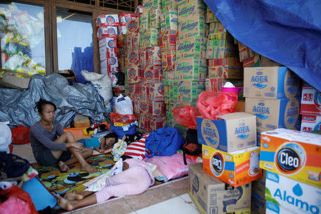 Children rest next to donated supplies outside a temporary evacuation center for people living near Mount Agung, a volcano on the highest alert level, at a sports arena in Klungkung, on the resort island of Bali, Indonesia, September 28, 2017. REUTERS/Darren Whiteside