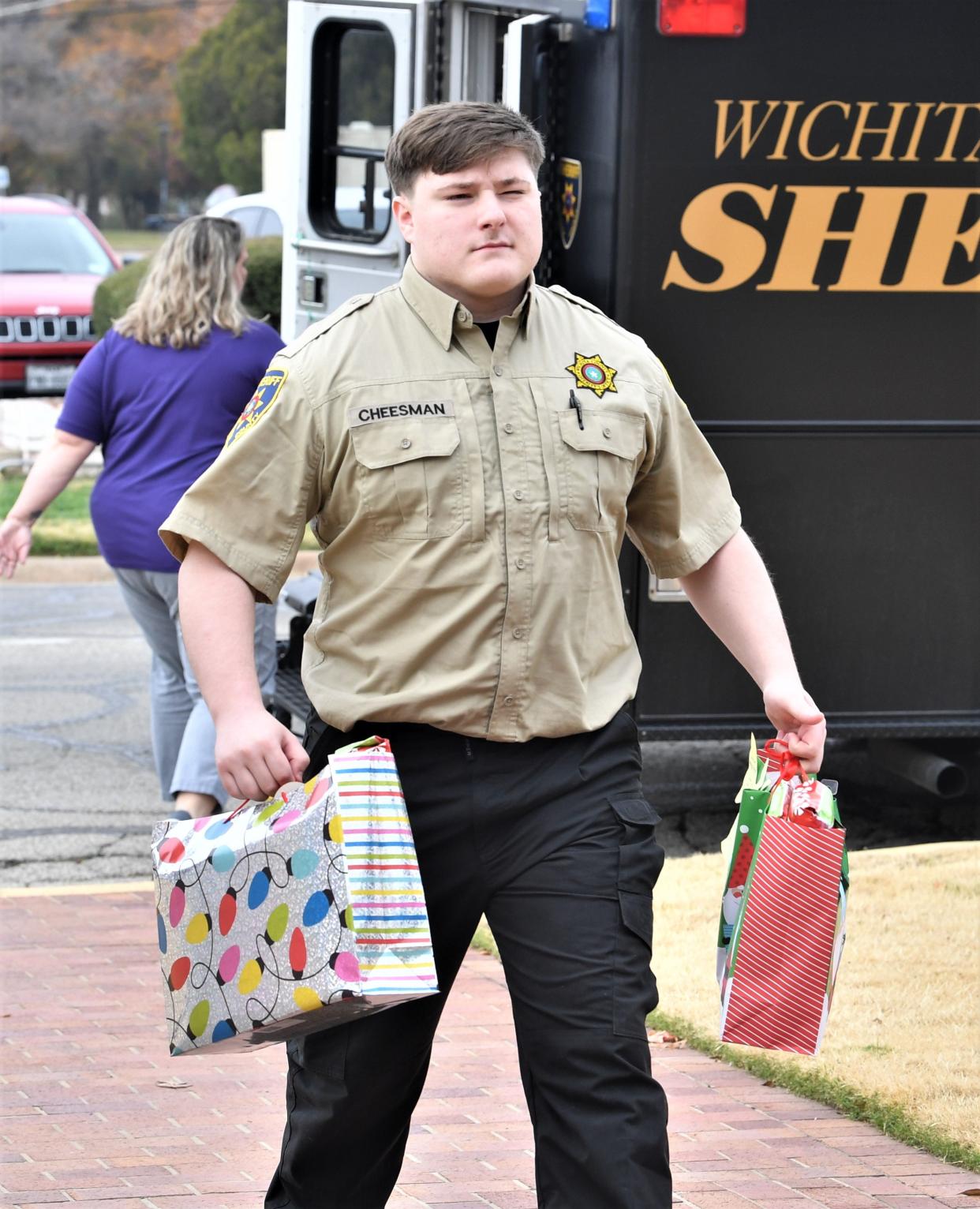 Wichita County Sheriff's Office Detention Officer Brenden Cheesman carries gifts into Patsy's House Wedneday as part of the office's annual Angel Tree Program.