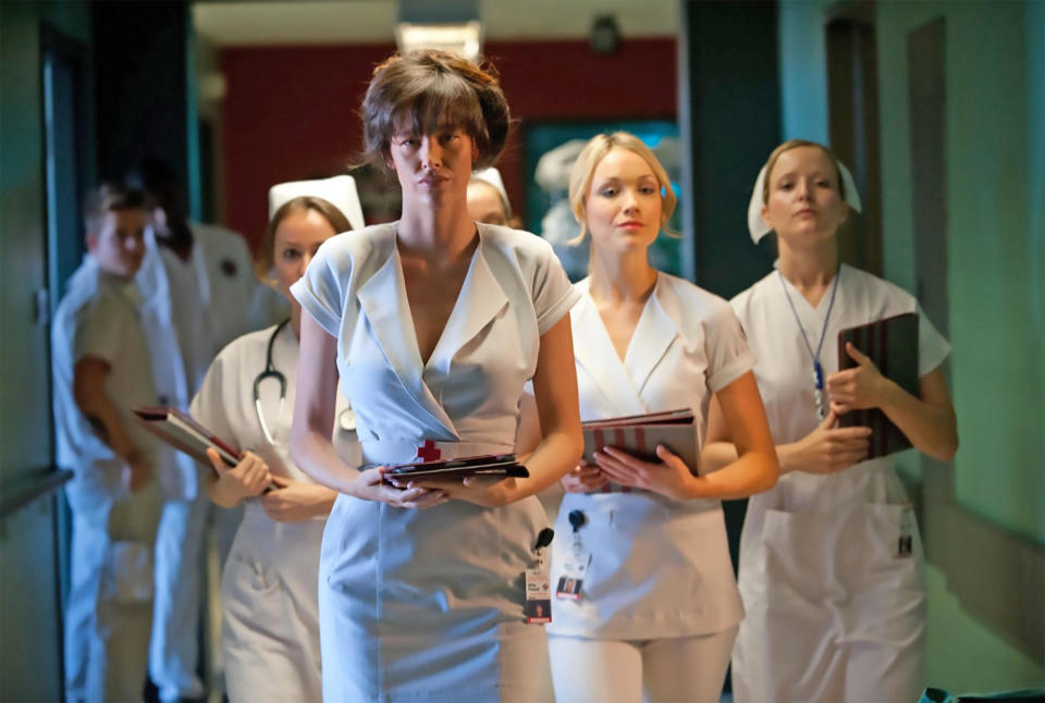 A group of nurses walk down a dimly lit hallway