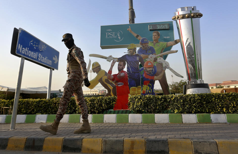 A paramilitary soldier patrols next to cutouts of cricket players displaying outside the National Stadium for the upcoming country's premier domestic Twenty20 tournament 'Pakistan Super League' in Karachi, Pakistan, Tuesday, Jan. 25, 2022. The Pakistan Cricket Board says "robust" COVID-19 health and safety protocols are in place ahead of its month-long domestic Twenty20 competition in Karachi and Lahore, with several foreign cricketers participating in a six-team event. (AP Photo/Fareed Khan)