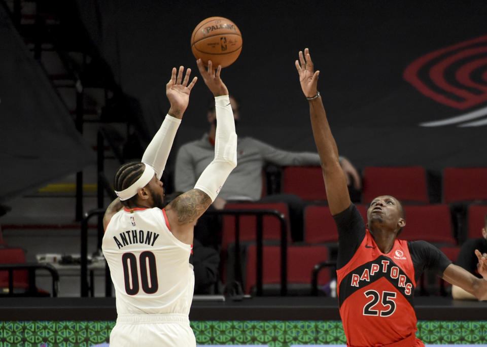 Portland Trail Blazers forward Carmelo Anthony, left, hits a basket over Toronto Raptors forward Chris Boucher, right, during the first half of an NBA basketball game in Portland, Ore., Monday, Jan. 11, 2021. (AP Photo/Steve Dykes)