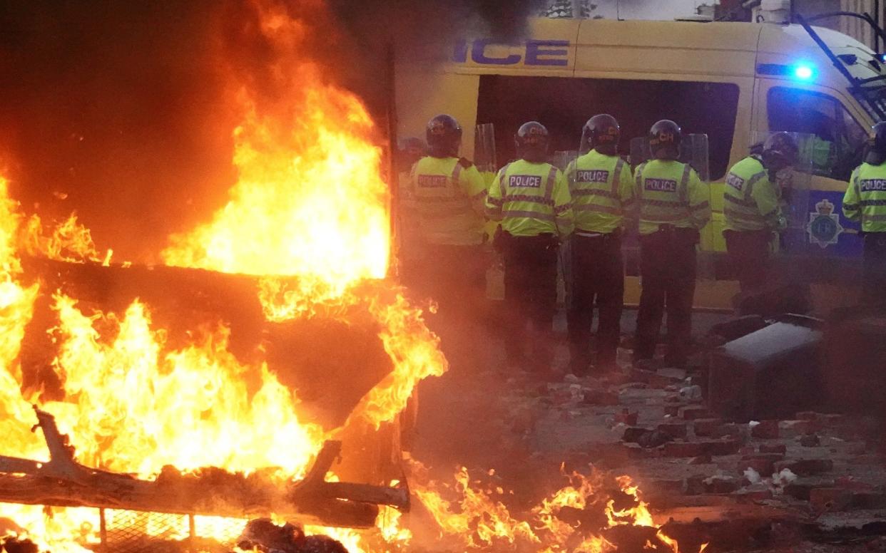 Riot police hold back protesters near a burning police vehicle after disorder broke out on July 30, 2024 in Southport