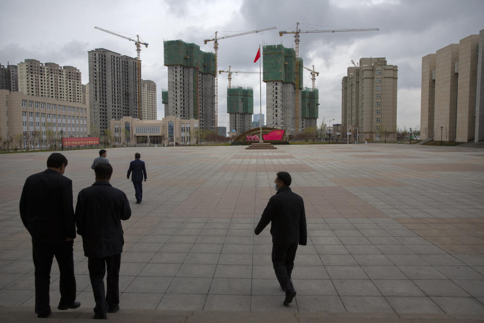 Chinese government officials walk across a plaza near a display with the Chinese flag at the Xinjiang Islamic Institute, as seen during a government organized visit for foreign journalists, in Urumqi in western China's Xinjiang Uyghur Autonomous Region on April 22, 2021. Under the weight of official policies, the future of Islam appears precarious in Xinjiang, a remote region facing Central Asia in China's northwest corner. Outside observers say scores of mosques have been demolished, which Beijing denies, and locals say the number of worshippers is on the decline. (AP Photo/Mark Schiefelbein)