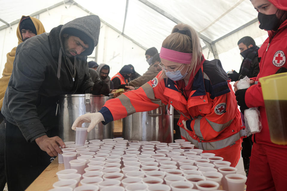 Migrants wait in a line to get food and warm beverages, at the Lipa camp, outside Bihac, Bosnia, Monday, Jan. 11, 2021. Aid workers say migrants staying at a camp in northwestern Bosnia have complained or respiratory and skin diseases after spending days in make-shift tents and containers amid freezing weather and snow blizzards. Most of the hundreds of migrants at the Lipa facility near Bosnia's border with Croatia on Monday have been accommodated in heated military tents following days of uncertainty after a fire gutted most of the camp on Dec. 23. (AP Photo/Kemal Softic)