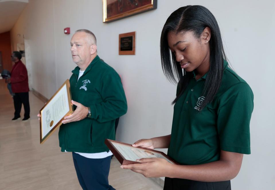 As her golf coach Martin Sims stands nearby, Kalista Bennett checks out the framed testimonial resolution that she and other members of the Detroit Cass Tech High School girls golf team received from the Detroit City Council during a session at the Coleman A. Young Municipal Center in downtown Detroit on Tuesday, November 7, 2023.