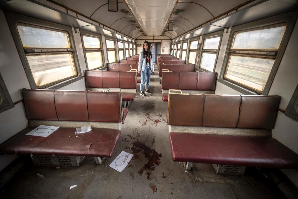 A woman stands in an empty train car.