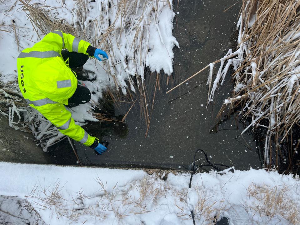 Owen Stefaniak, a scientist with the U.S. Geological Survey, collects stream samples near the Air Guard 128th Air Refueling Wing base, 1919 E Grange Ave., during a winter storm. A recent study shows that airplane deicers are polluting waterways with phosphorus.