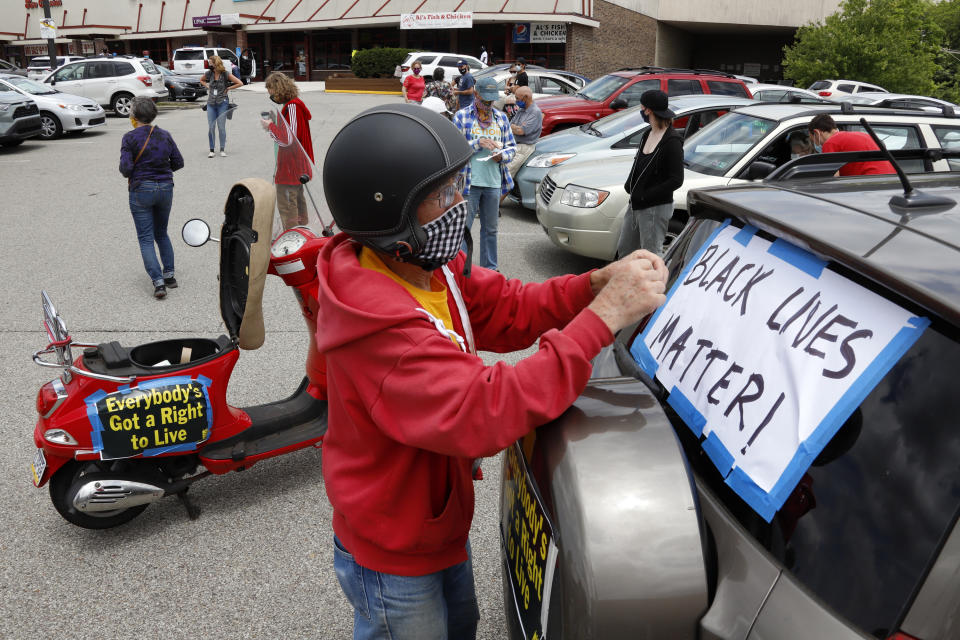 FILE - In this June 14, 2020, file photo, Mel Packer of Pittsburgh tapes a sign on a vehicle in the parking lot of a Shop & Save in downtown Pittsburgh in preparation for the Pennsylvania Poor People's Campaign: National Call for Moral Revival. A national coalition of labor unions, along with racial and social justice organizations, will stage a mass walkout from work July 20, as part of an ongoing reckoning on systemic racism and police brutality in the U.S. (AP Photo/Gene J. Puskar, File)