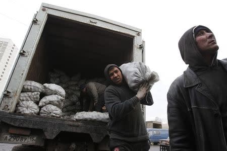 Migrant workers work unload potato sacks at a vegetable market on the outskirts of Moscow in this November 11 2011 file photo. REUTERS/Denis Sinyakov/Files