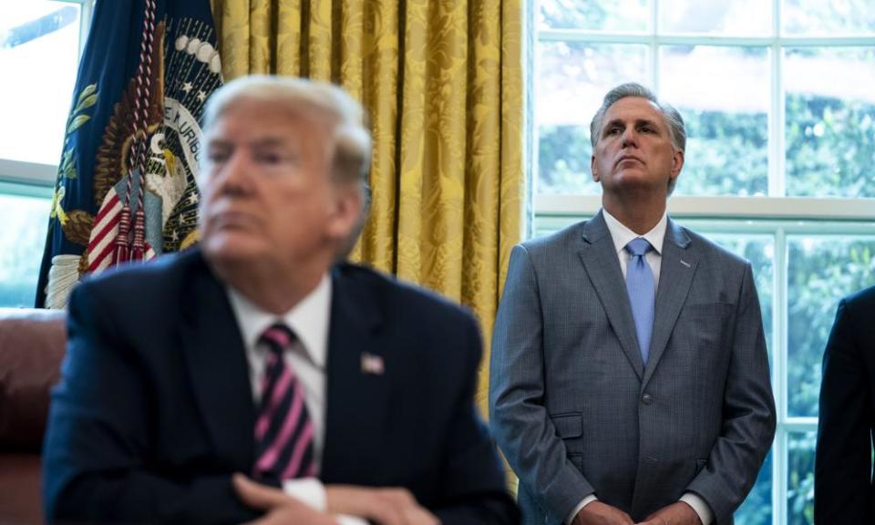 Kevin McCarthy stands behind Donald Trump.