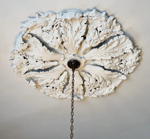 A white gypsum medallion surrounds a hanging light fixture.