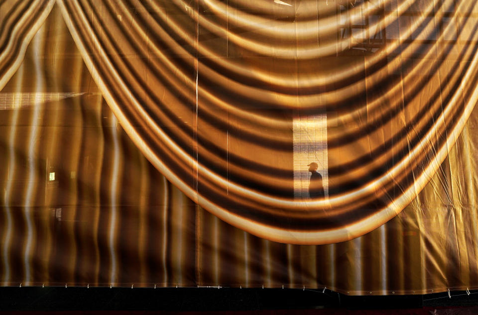 A silhouette of a man appears through a translucent gold curtain set up on Hollywood Blvd. for Sunday's 94th Academy Awards arrivals, Wednesday, March 23, 2022, in Los Angeles. (AP Photo/Chris Pizzello)