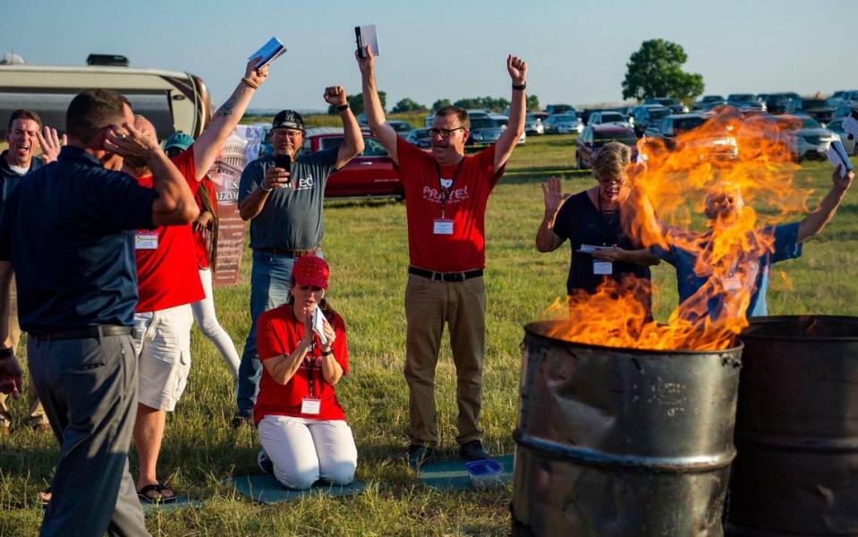 Attendees from across the U.S. and event leaders lift up their hands as they pray over names on cards, Friday, July 22, 2021, at the Prayer at the Heart of America event in Lebanon, Kansas. The cards were burned after the names were prayed for during the symbolic offering by fire at the end of the event.