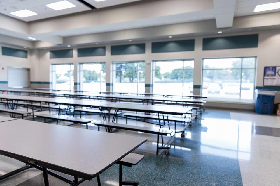 Clean, empty school cafeteria with large windows is ready for students.