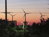 The sun sets behind spinning land-based wind turbines in Atlantic City, N.J., on Dec. 13, 2023. On April 24, 2024, eight Jersey Shore towns wrote to New Jersey utility regulators saying that a proposed wind farm off Long Beach Island will be costlier than expected. (AP Photo/Wayne Parry)