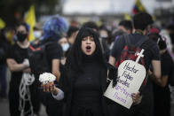 Holding a sign in the shape of a headstone with the name of one of the victims of the ongoing violence, and dressed as a widow, a demonstrator marches during an anti-government protest in Bogota, Colombia, Wednesday, May 12, 2021. Colombians have taken to the streets for weeks across the country after the government proposed tax increases on public services, fuel, wages and pensions, but have continued even after President Ivan Duque walked back the tax hike. (AP Photo/Ivan Valencia)