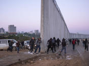 Palestinians cross into Israel from the West Bank through an opening in the Israeli separation barrier between the West Bank town of Qalqilya and the Israeli Kibbutz Eyal Sunday, Feb. 27, 2022. Twenty years after Israel decided to built its controversial separation barrier amid a wave of Palestinian attacks, it remains in place, even as Israel encourages its own citizens to settle on both sides and admits tens of thousands of Palestinian laborers. (AP Photo/Oded Balilty)