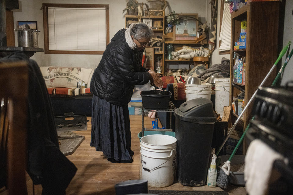 Marilyn Help-Hood washes her hands with a bucket after feeding her livestock in Tohlakai, N.M.,  on March 13, 2023. (Sharon Chischilly for NBC News)