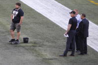 Officials assess the location where the CFL goal post holes were, before an NFL preseason football game between the Oakland Raiders and the Green Bay Packers in Winnipeg, Manitoba, Thursday, Aug. 22, 2019. In the NFL the field goal posts are located at the back of the end zone and the Canadian Football League has the posts at the front of the end zone. (John Woods/The Canadian Press via AP)