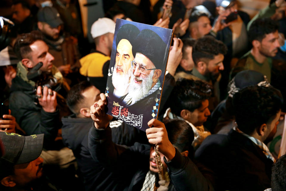 Members of the Popular Mobilization Forces (PMF) and their supporters chant slogans against the United States at Baghdad's international airport on Saturday, Jan. 2, 2021, for the anniversary of the killing of Abu Mahdi al-Muhandis, deputy commander of the PMF, and Gen. Qassem Soleimani, head of Iran's Quds Force in a U.S. airstrike. The poster depicting late Iranian revolutionary founder Ayatollah Khomeini, left, and Supreme Leader Ayatollah Ali Khamenei. (AP Photo/Khalid Mohammed)