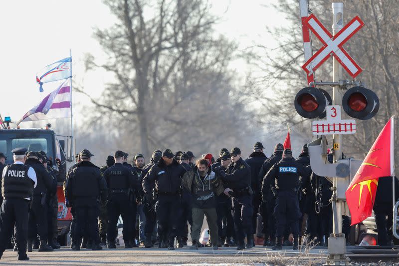 Police officers make an arrest during a raid on a Tyendinaga Mohawk Territory camp next to a railway crossing in Tyendinaga