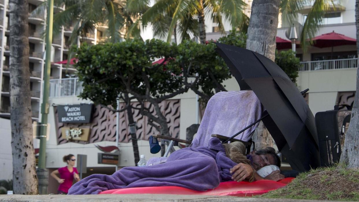 PHOTO: In this Dec. 20, 2014 file photo, a homeless man sleeps by Waikiki beach in Honolulu. (Nicholas Kamm/AFP via Getty Images, FILE)