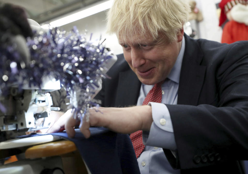 Britain's Prime Minister Boris Johnson tries to operate a sewing machine decorated for Christmas, during an election campaign stop at John Smedley Mill in Matlock, England, Thursday Dec. 5, 2019. The UK goes to the polls in a General Election on Dec. 12. (Hannah McKay/Pool via AP)