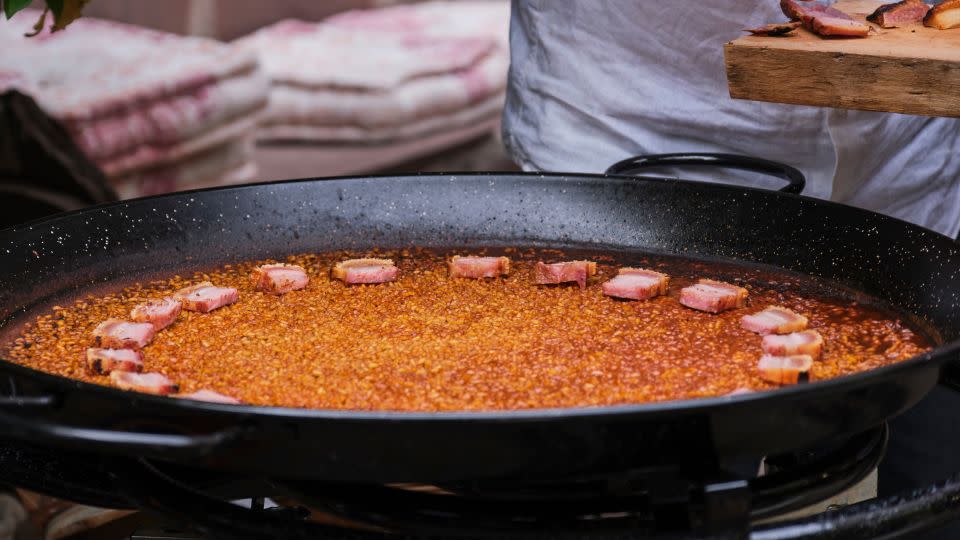 A rice dish made in a paella pan with pork belly — notably <em>not</em> true Valencian paella, according to José Andrés. - Warner Bros. Discovery