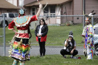 In this photo taken Saturday, April 4, 2020, Wicahpi Cuny, a Dakota and Lakota tribal member, dances during a live streamed powwow as her brother Wakiyan Cuny, right, mother Tera Baker, filming the live stream, and grandmother Lisa Dobyns, look on in Puyallup, Wash. The largest powwows in the country have been canceled or postponed amid the spread of the coronavirus. Tribal members have found a new outlet online with the Social Distance Powwow. They're sharing videos of colorful displays of culture and tradition that are at their essence meant to uplift people during difficult times. (AP Photo/Elaine Thompson)
