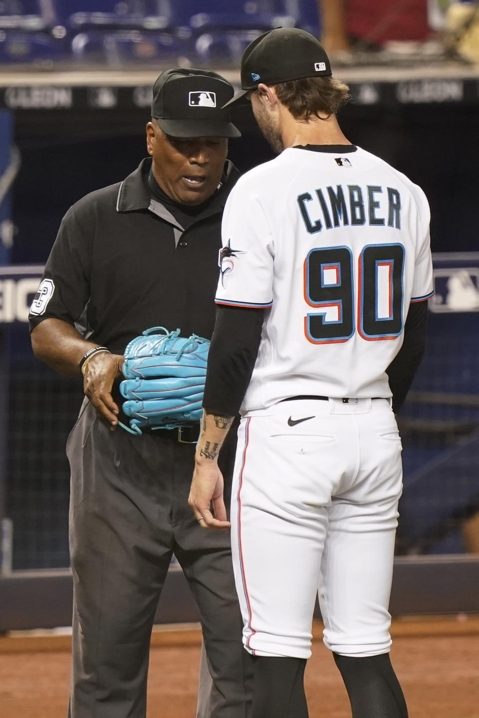 MLB umpire Laz Diaz checks the glove of Miami Marlins relief pitcher Adam Cimber (90) during the sixth inning of a baseball game against the Toronto Blue Jays, Wednesday, June 23, 2021, in Miami. (AP Photo/Marta Lavandier)
