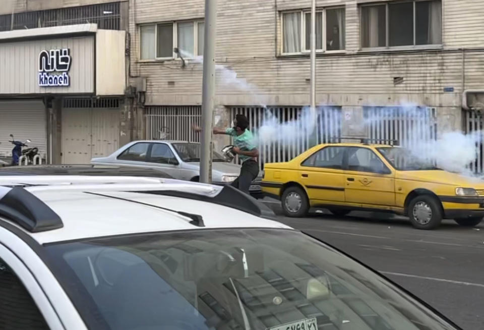 In this Tuesday, Sept. 20, 2022, photo taken by an individual not employed by the Associated Press and obtained by the AP outside Iran, a protester throws a tear gas back at the anti-riot police during a protest over the death of a young woman who had been detained for violating the country's conservative dress code, in downtown Tehran, Iran. Iran faced international criticism on Tuesday over the death of a woman held by its morality police, which ignited three days of protests, including clashes with security forces in the capital and other unrest that claimed at least three lives. (AP Photo)