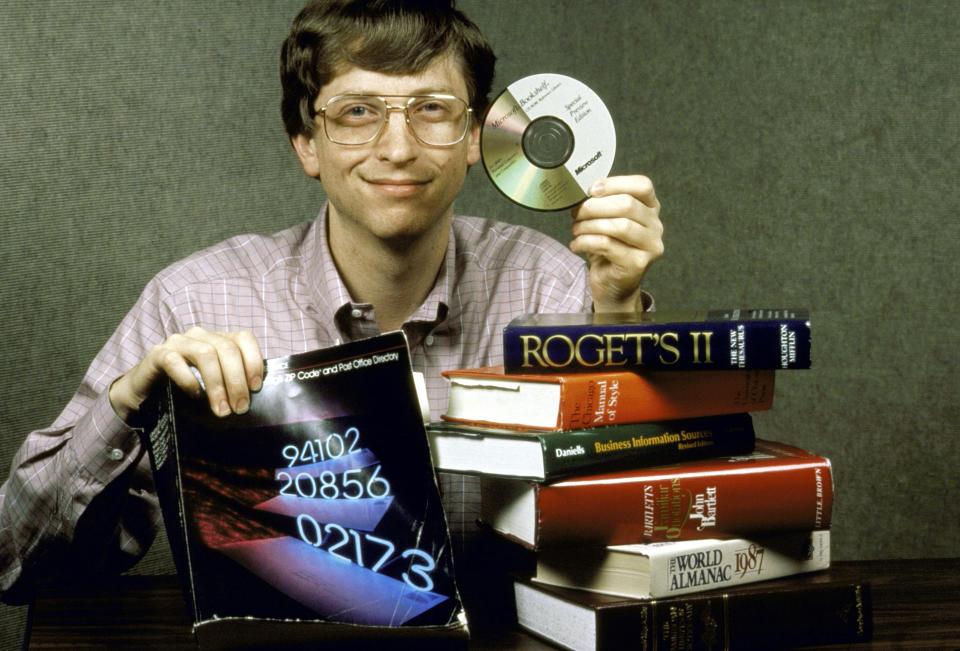 Microsoft Chairman Bill Gates, behind a pile of books, holds up Bookshelf, a new compact disc for computers which holds all the information contained in the books pictured.  (Photo by Doug Wilson/The LIFE Images Collection via Getty Images/Getty Images)