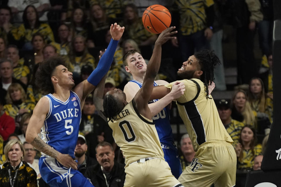 Duke's Tyrese Proctor (5) knocks the ball away from Wake Forest's Kevin Miller (0) as Duke's Kyle Filipowski (30) and Wake Forest's Efton Reid III (4) battle during the second half of an NCAA college basketball game in Winston-Salem, N.C., Saturday, Feb. 24, 2024. (AP Photo/Chuck Burton)