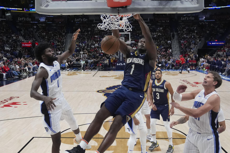 New Orleans Pelicans forward Zion Williamson (1) slam dunks between Orlando Magic forward Jonathan Isaac (1) and center Moritz Wagner in the second half of an NBA basketball game in New Orleans, Wednesday, April 3, 2024. The Magic won 117-108. (AP Photo/Gerald Herbert)