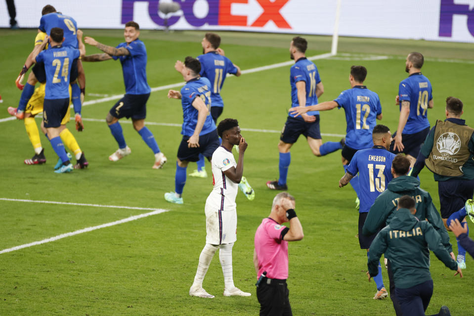 FILE - England's Bukayo Saka reacts after missing a penalty as Italy celebrate after a penalty shootout at the Euro 2020 soccer championship final between England and Italy at Wembley stadium in London, Sunday, July 11, 2021. Missing penalties in a major international soccer final was bad enough for three Black players, Marcus Rashford, Jadon Sancho and Bukayo Saka, who were on England's national team. Being subjected to a torrent of racial abuse on social media in the aftermath made it even worse. (John Sibley/Pool Photo via AP, File)