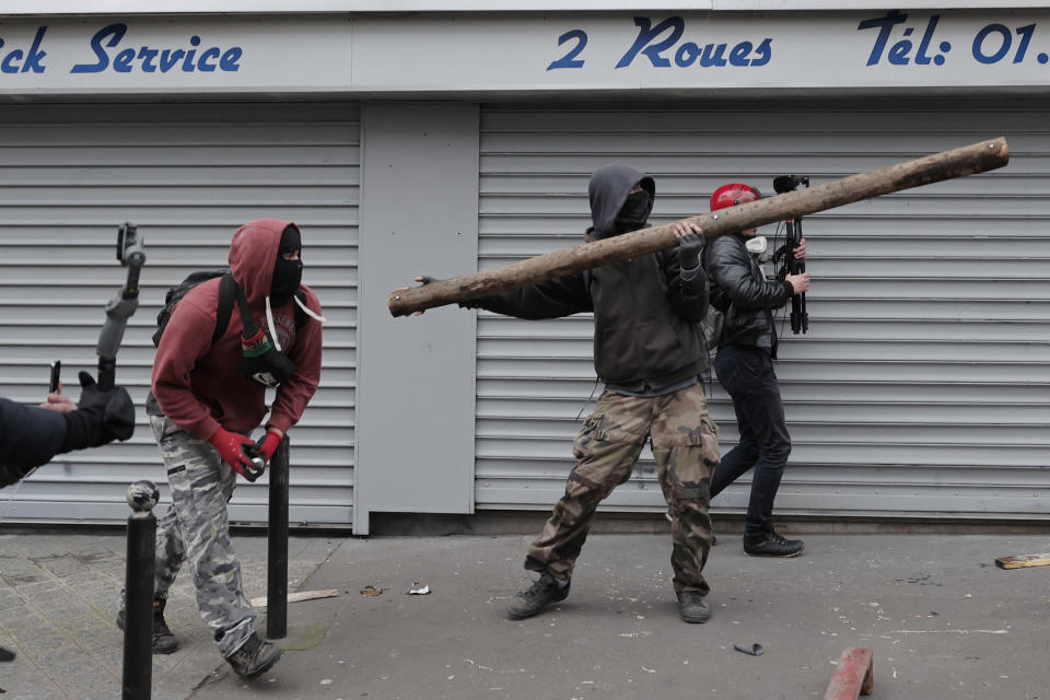Youths throw wooden pieces during a demonstration against pension changes in Paris, Thursday, Jan. 19, 2023. Workers in many French cities took to the streets Thursday to reject proposed pension changes that would push back the retirement age, amid a day of nationwide strikes and protests seen as a major test for Emmanuel Macron and his presidency. (AP Photo/Lewis Joly)