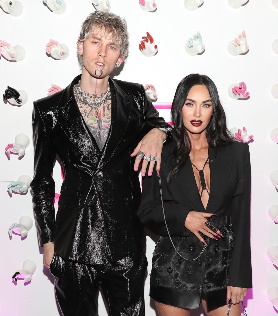 Machine Gun Kelly rests his arm on Megan's shoulder and shows off nail chain