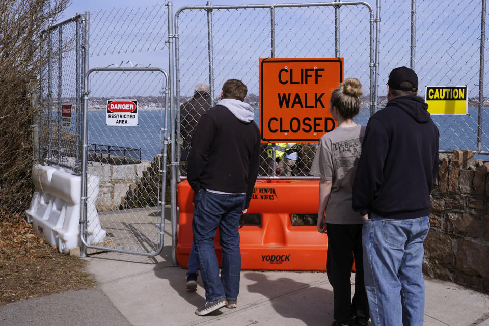 FILE - Visitors look through a chainlink barricade towards a collapse portion of the historic Cliff Walk, March 15, 2022, in Newport, R.I. Gov. Dan McKee issued a disaster declaration on Tuesday, June 13, 2023, that will allow the state Department of Transportation to apply for $10 million in emergency relief funds from the Federal Highway Administration. (AP Photo/Charles Krupa, File)