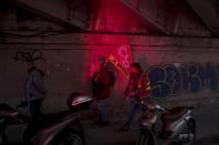 Protesters are illuminated by light from flares during a demonstration in Marseille, southern France, Friday, Jan. 24, 2020. French unions are holding last-ditch strikes and protests around the country Friday as the government unveils a divisive bill redesigning the national retirement system. (AP Photo/Daniel Cole)