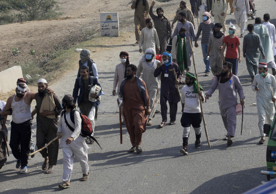 Supporters of Tehreek-e-Labiak Pakistan, a radical Islamist party, help their colleague, left, who was injured in clashes with police, during their protest march toward Islamabad, on a highway in the town of Sadhuke, in eastern Pakistan, Wednesday, Oct. 27, 2021. Violence at the anti-France Islamist rally in Sadhuke left at least one police officer and two demonstrators dead. ​They demanded the expulsion of France's envoy to Pakistan over publication of caricatures of Islam's Prophet Muhammad in France. (AP Photo/K.M. Chaudary)